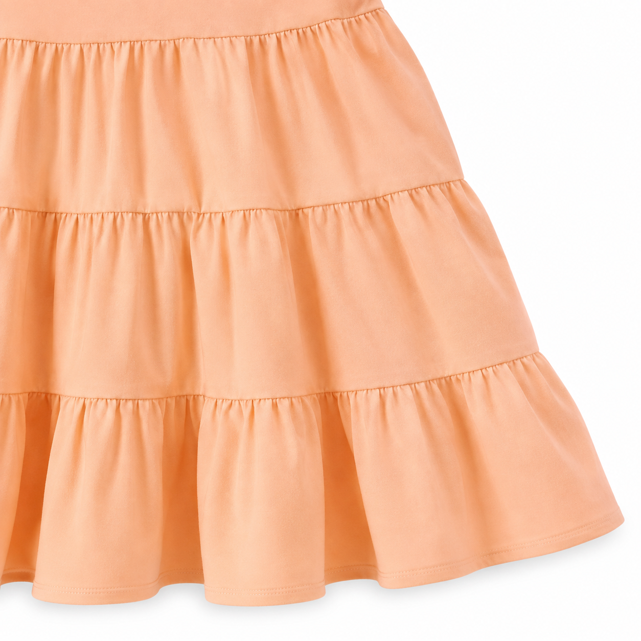 Close-up of the gathered tiered skirt and hem detail on the peach girls dress.