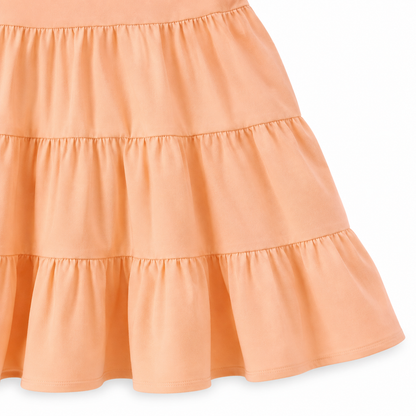 Close-up of the gathered tiered skirt and hem detail on the peach girls dress.