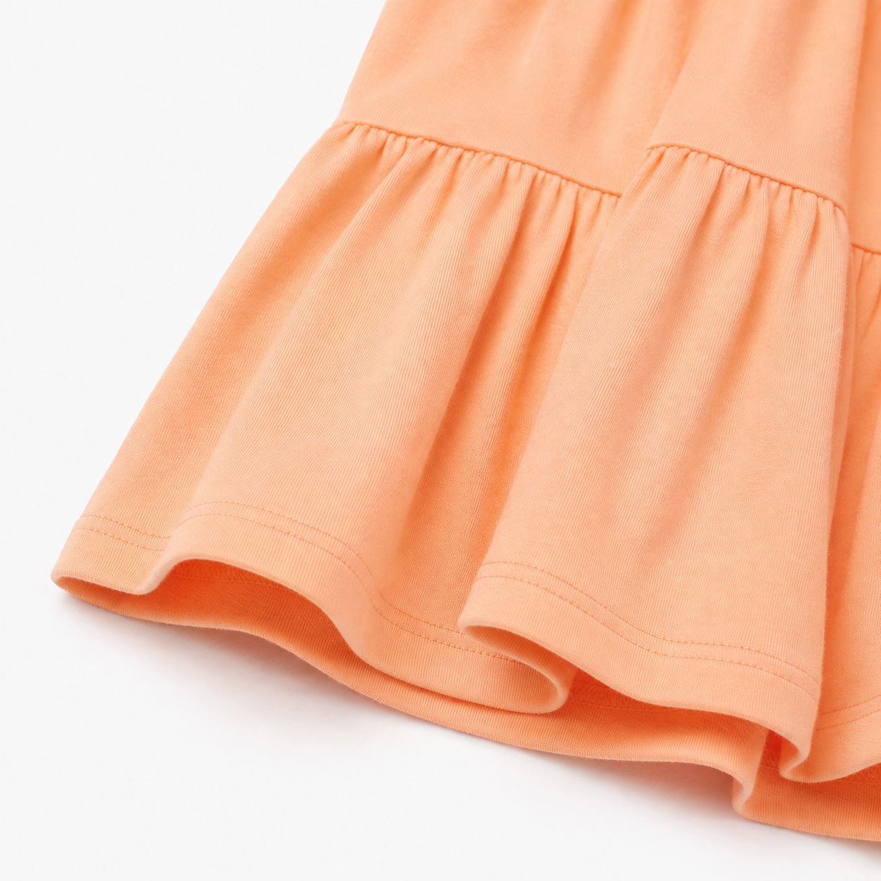 Close-up of the elastic cuff and cotton fabric texture on the peach long sleeve dress.