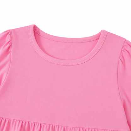 Close-up of the round neckline and gathered shoulder detail on the pink girls dress.