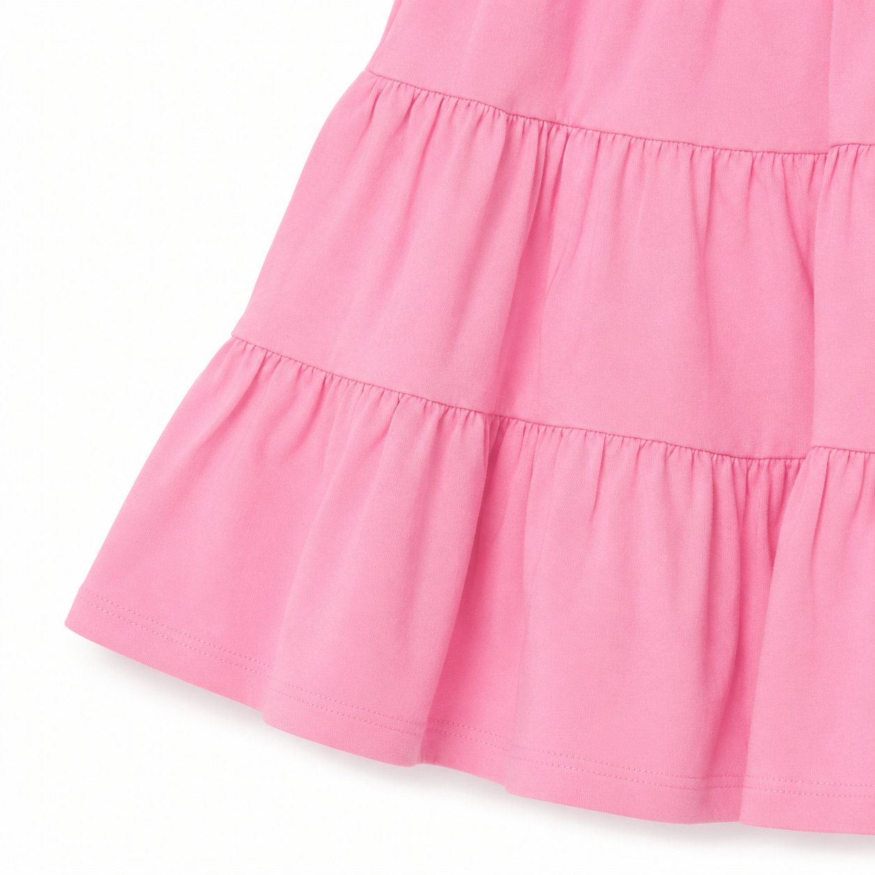 Close-up of the gathered tiered skirt and hem detail on the pink girls dress.